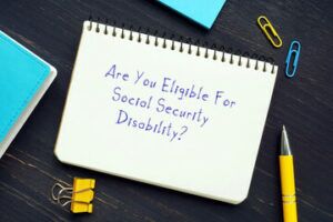 writing pad with the word -are you eliginle for social security disability- with paper clips, and pen around