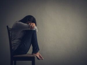 Depressed woman sitting on a chair in dark room